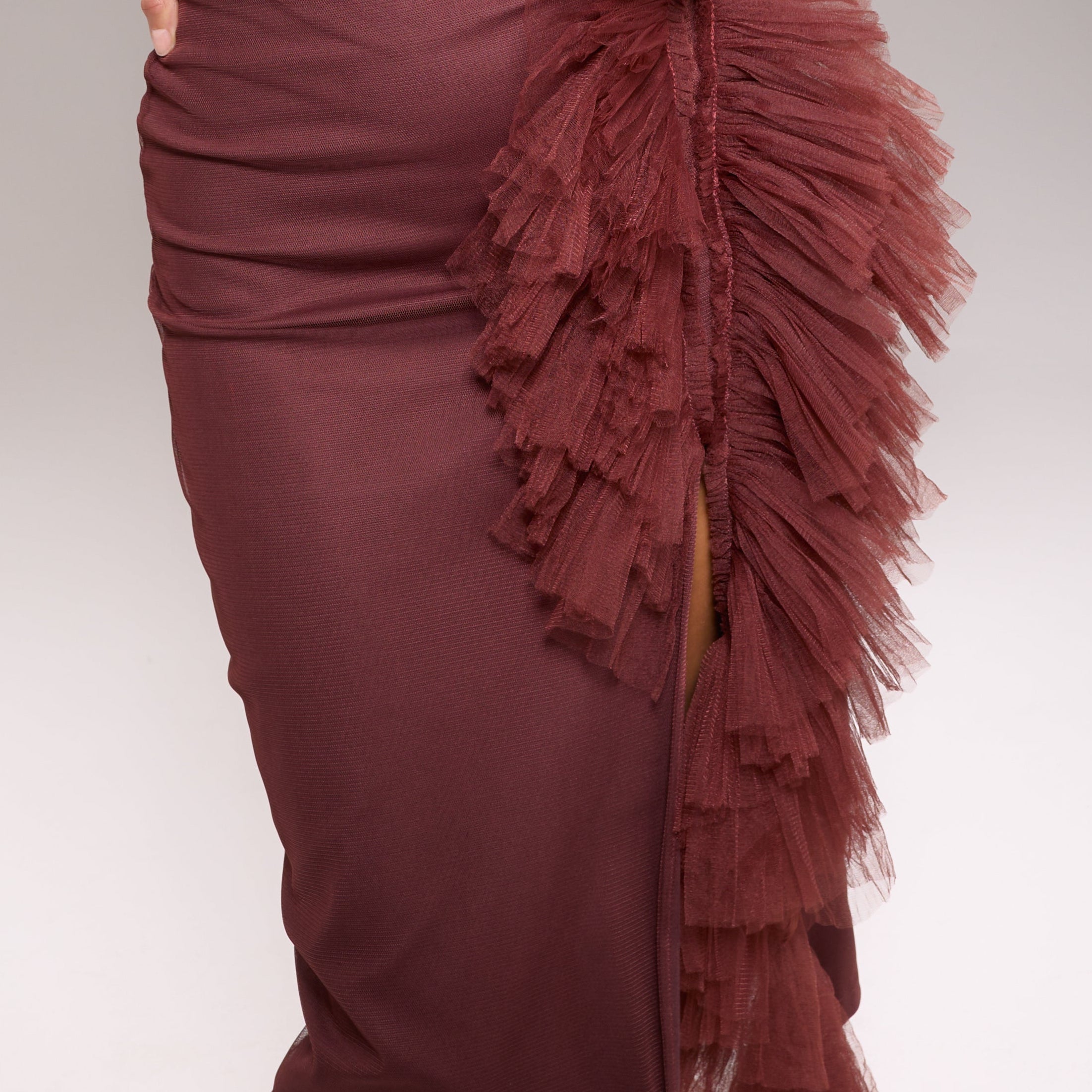A model wearing a maroon skirt with tulle details. The skirt is midi length and has a back zipper.